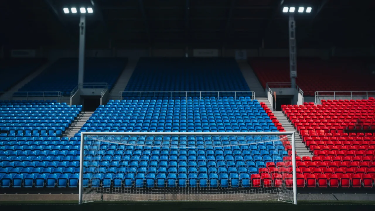 Empty away end seats in a single bright colour behind a goal net